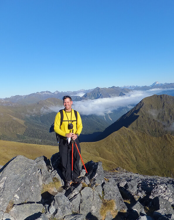 jason standing on rocks with a mountain range behind